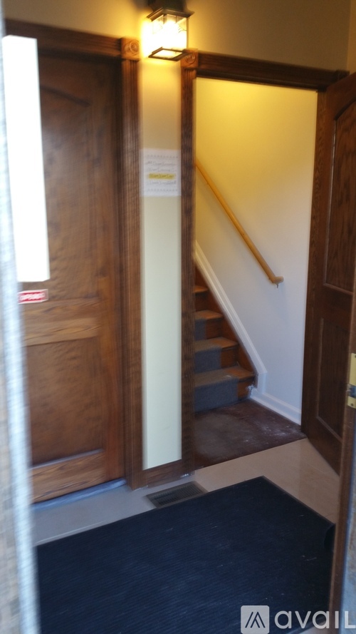 A hallway with a staircase and a light on the wall.
