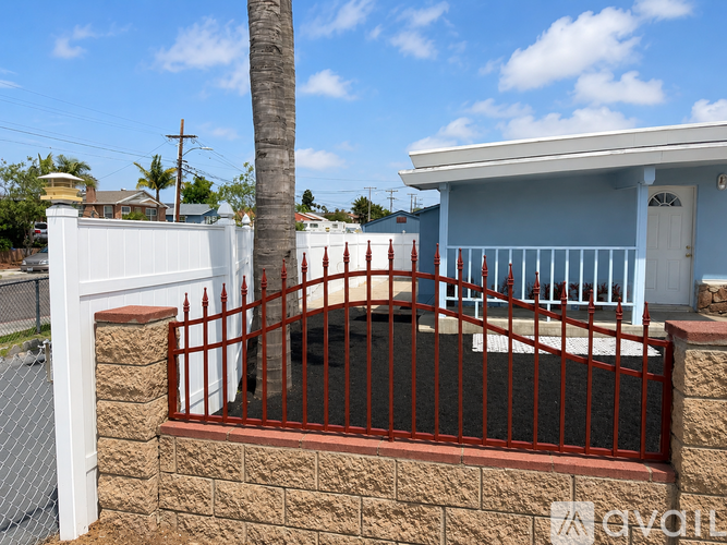 A blue house with a red fence and a white gate.