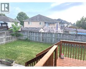 A wooden deck overlooks a backyard with a pool and houses in the background.