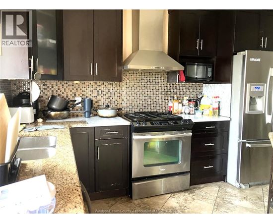 A kitchen with a black stove top oven and black cabinets.