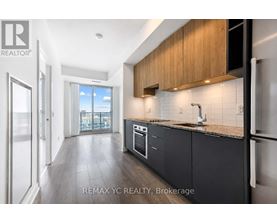 A modern kitchen with dark wood cabinets and a marble backsplash.