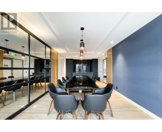A modern dining room with a glass wall and a wooden floor.