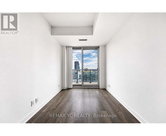 A spacious, empty room with a view of the city through a large window.
