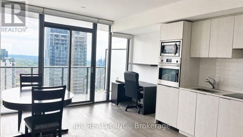 A modern kitchen with a dining table and chairs, a microwave, and a view of the city.