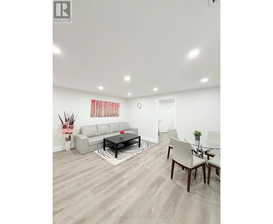 A living room with a grey sofa, a glass table and a white chair.