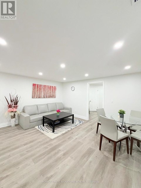 A living room with a grey sofa, a glass table and a white chair.