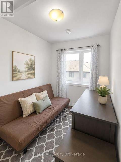 A living room with a brown couch and a painting on the wall.
