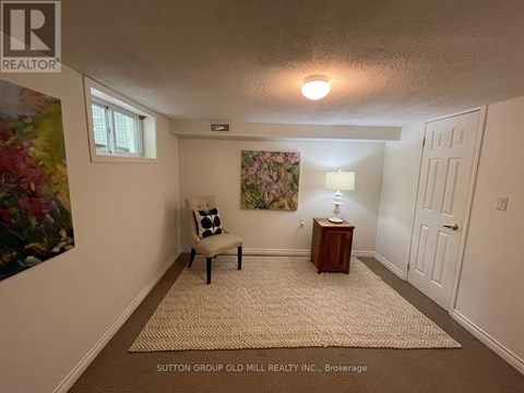 A room with a chair and a lamp on a side table.