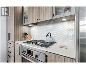 A modern kitchen with a stove top and wooden cabinets.