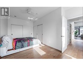 A bedroom with a bed, a nightstand, and a door leading to another room.