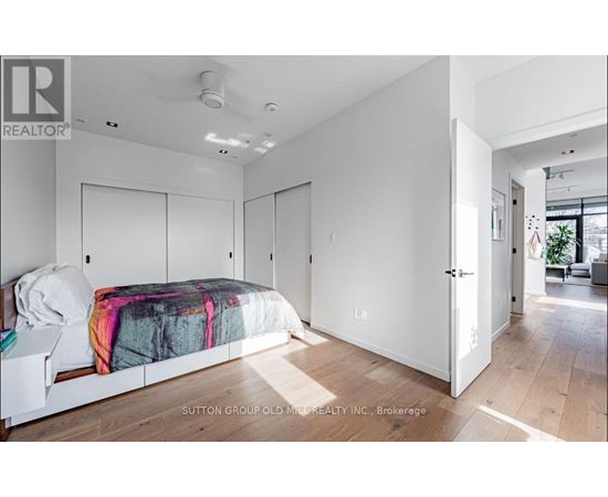 A bedroom with a bed, a nightstand, and a door leading to another room.
