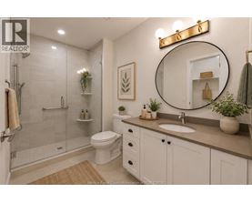 A bathroom with a toilet, sink, mirror, and shower.
