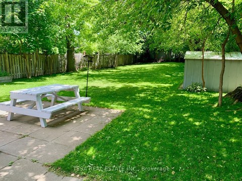 A white picnic table is in the middle of a green yard.