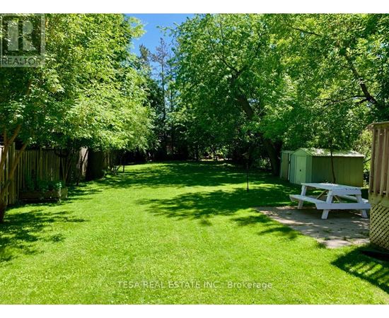 A backyard with a white bench and a wooden fence.