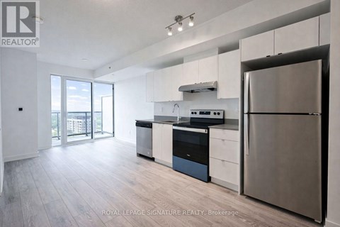 A modern kitchen with stainless steel appliances and wooden flooring.
