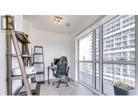 A room with a desk, chair, and a window overlooking a building.