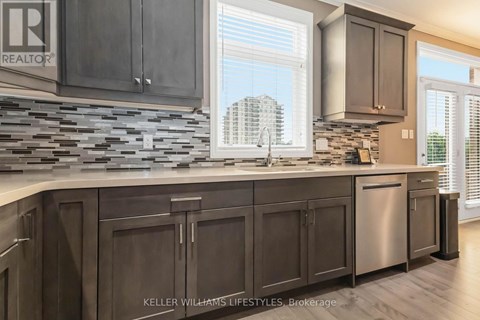 A kitchen with dark wood cabinets and a stone backsplash.