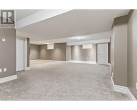 A spacious, empty room with a carpeted floor and beige walls.