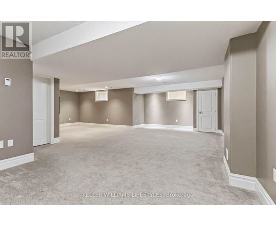 A spacious, empty room with a carpeted floor and beige walls.