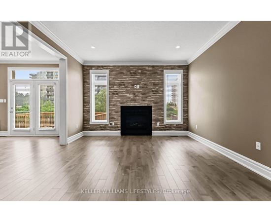 A spacious living room with a stone fireplace and hardwood floors.