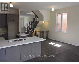 A kitchen with a sink and a staircase.