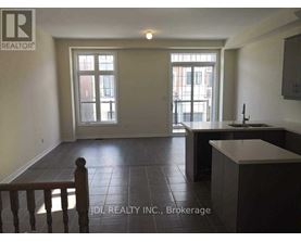 A spacious room with a kitchen area and a dining table.