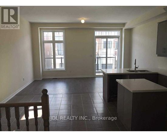 A spacious room with a kitchen area and a dining table.