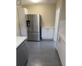 A kitchen with a stainless steel refrigerator and cabinets.