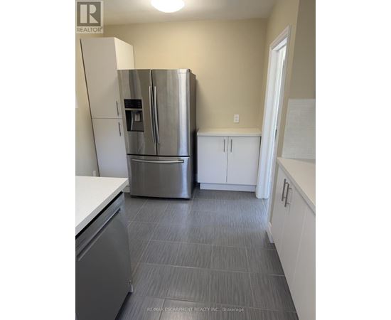 A kitchen with a stainless steel refrigerator and cabinets.