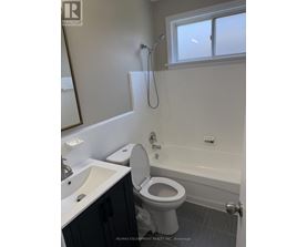 A white toilet in a bathroom with a sink and a window.