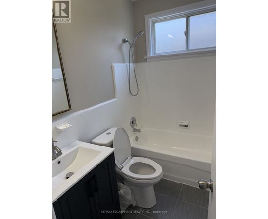A white toilet in a bathroom with a sink and a window.