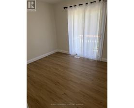 A room with wooden flooring and white curtains.