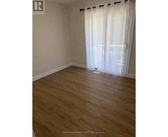 A room with wooden flooring and white curtains.
