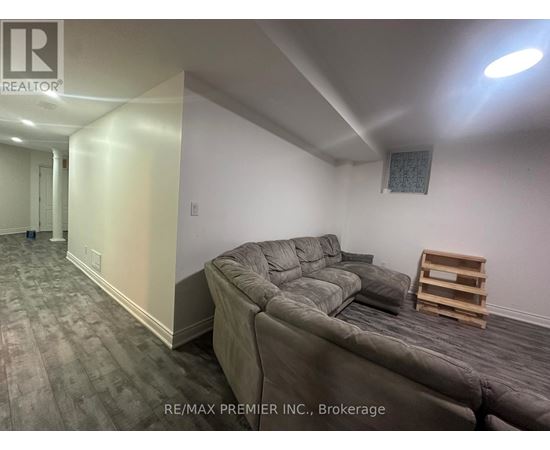 A living room with a grey couch and a wooden stool.