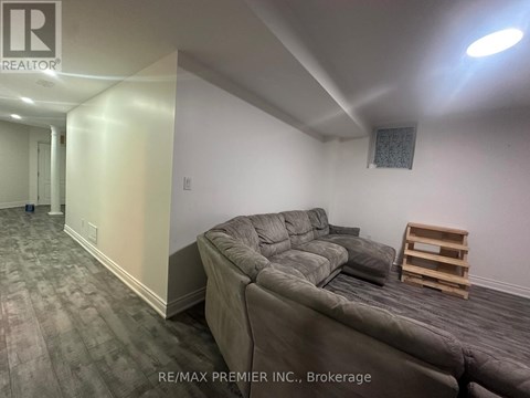 A living room with a grey couch and a wooden stool.