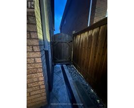 A wooden fence and a brick wall with a metal gate.