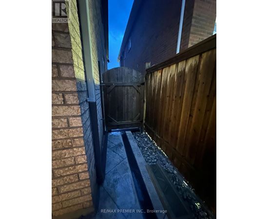 A wooden fence and a brick wall with a metal gate.