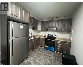 A kitchen with a black refrigerator and a black chair.