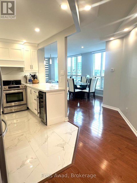 A modern kitchen with white cabinets and a wooden floor.