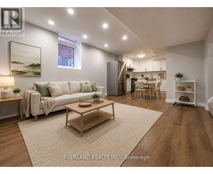 A well-lit, modern living room with a white sofa, wooden coffee table, and a painting on the wall.