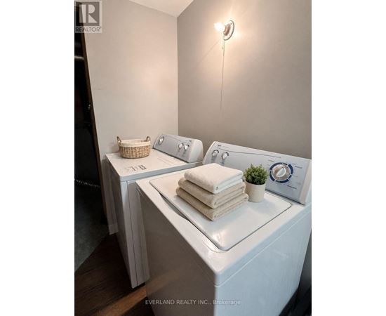 A laundry room with a washer and dryer, a basket, and towels.