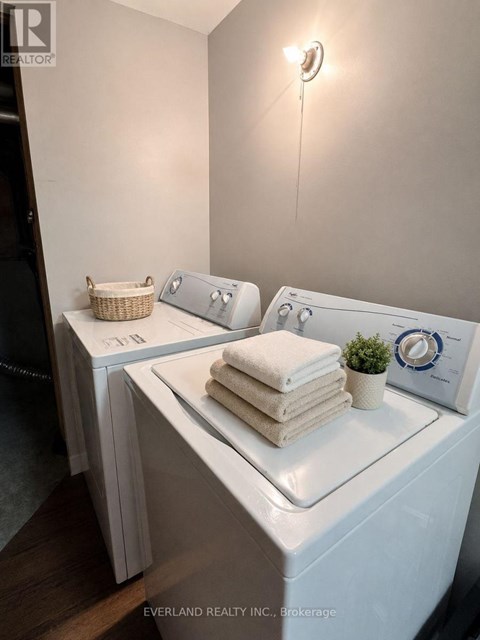 A laundry room with a washer and dryer, a basket, and towels.
