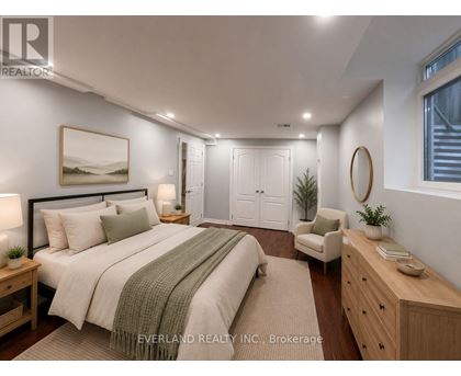 A bedroom with a large bed, a chair, and a painting on the wall.