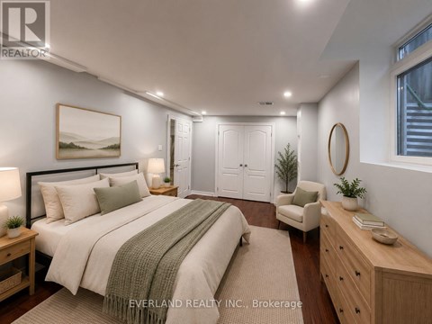 A bedroom with a large bed, a chair, and a painting on the wall.
