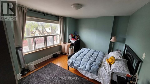 A bedroom with a bed, a window, and a teddy bear on the bed.