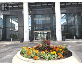 A flower bed in front of a glass building with the word REALTOR on it.