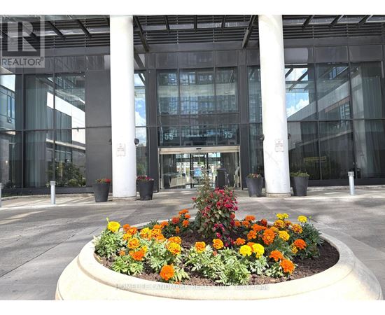 A flower bed in front of a glass building with the word REALTOR on it.