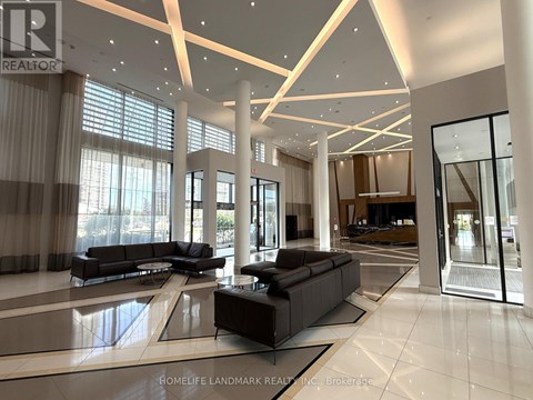 A spacious living room with a black sofa set and a glass door.
