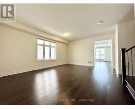 A spacious room with wooden floors and two windows.