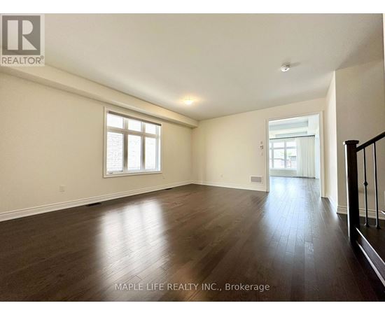 A spacious room with wooden floors and two windows.